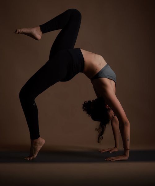 Woman in a calm yoga pose against a dark background with amber light.